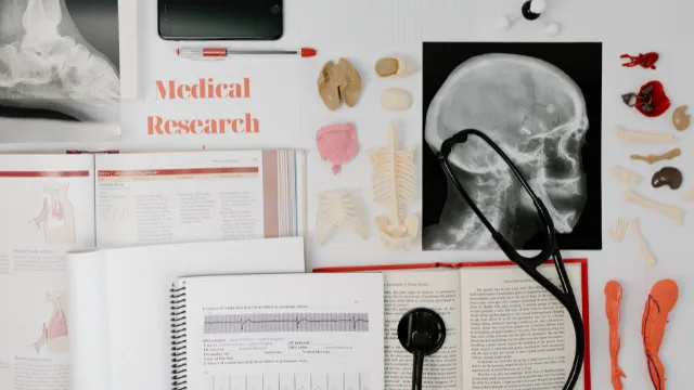 A desk with medical textbooks, X-rays, and anatomical models, symbolizing the deep research required to choose the right state for the NCLEX and avoid saturated, competitive markets.
