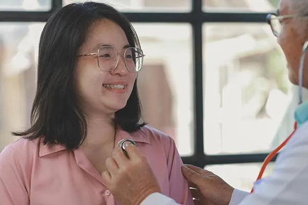 Employee smiling during a checkup, symbolizing health and wellness for SMEs in 2025