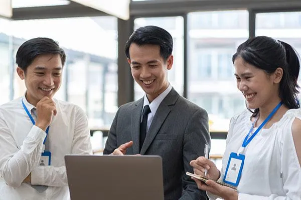 HR associate smiling with a laptop, onboarding new employees, highlighting better health benefits as a key hiring feature.