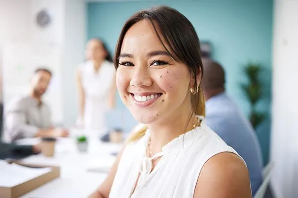 Female employee flashing a confident smile, symbolizing the value of dental benefits and oral health care