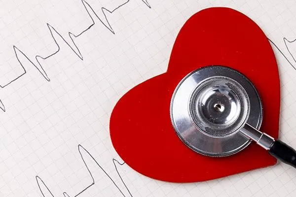 Red heart with a stethoscope on top and a heartbeat graph in the background, symbolizing workplace initiatives for heart health this Valentine’s