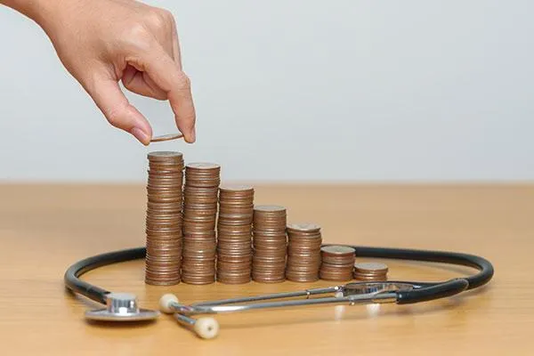 Stethoscope on a table with stacks of coins