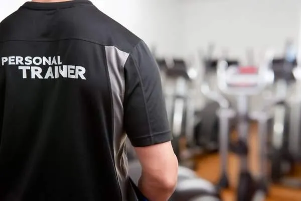 Personal Trainer motiviert Kunden in einem Fitnessstudio in München während eines individuellen Trainings.