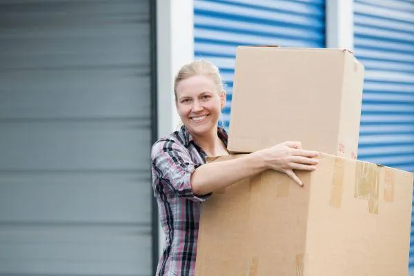 A woman holding boxes at a self-storage facility