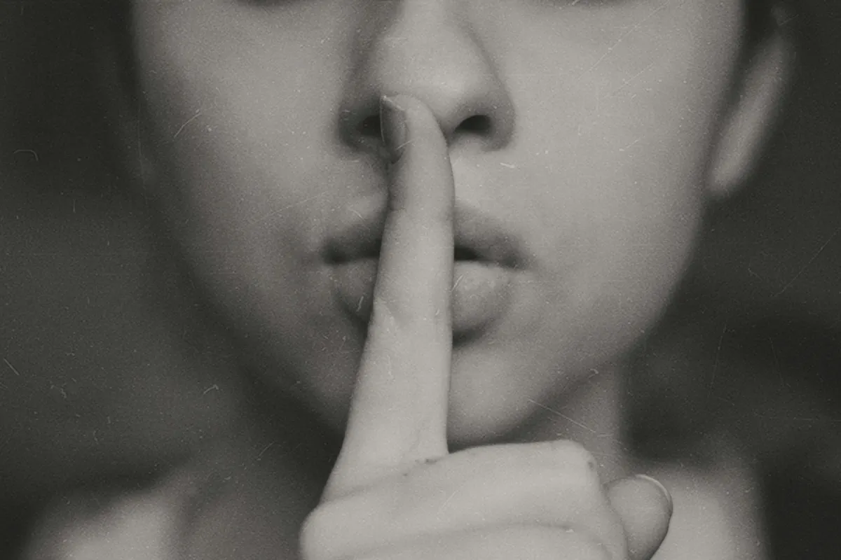 A woman with her hand to her lips in silence