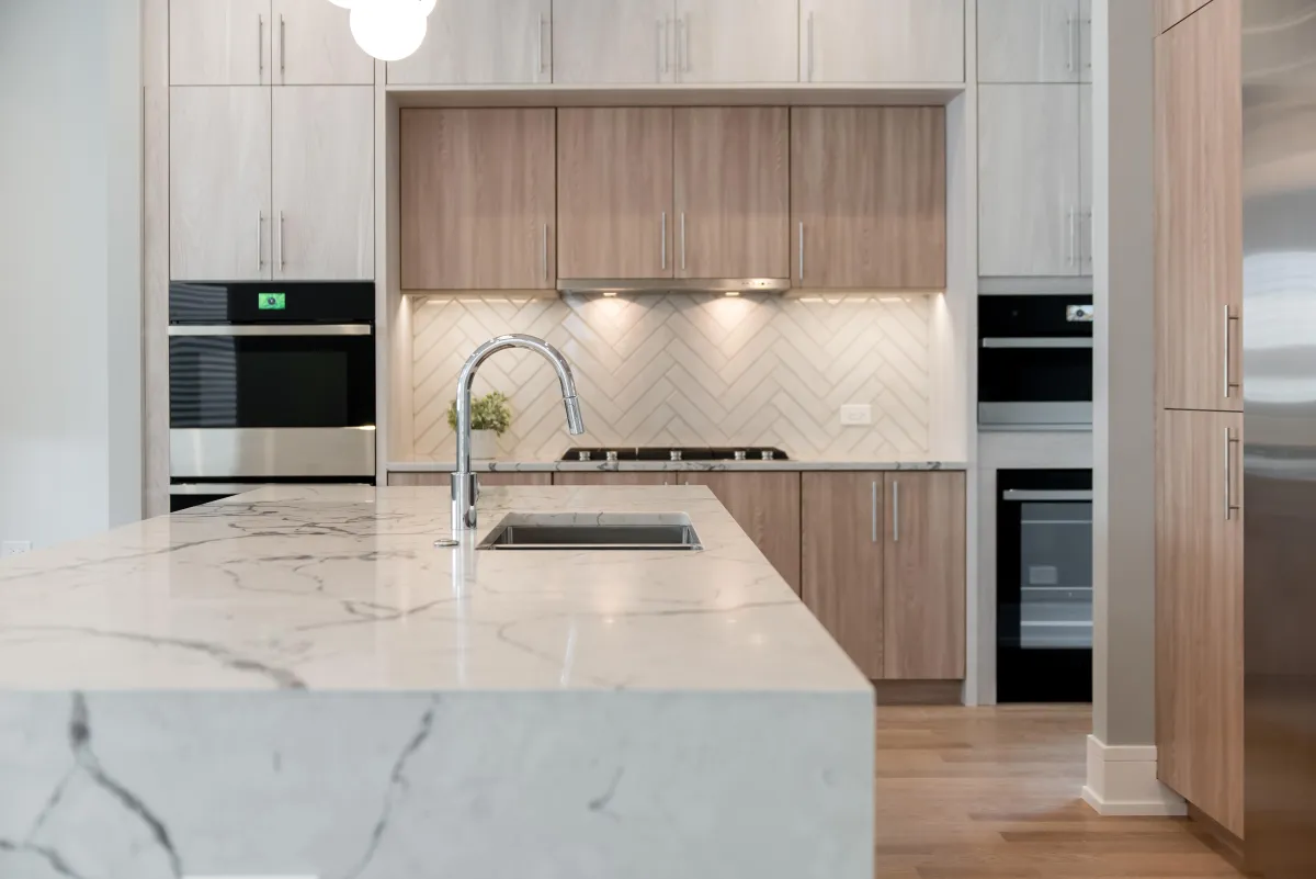 "Modern kitchen remodel featuring quartz countertops, custom white cabinetry, stainless steel appliances, and pendant lighting – by Sweet Home Improvements"