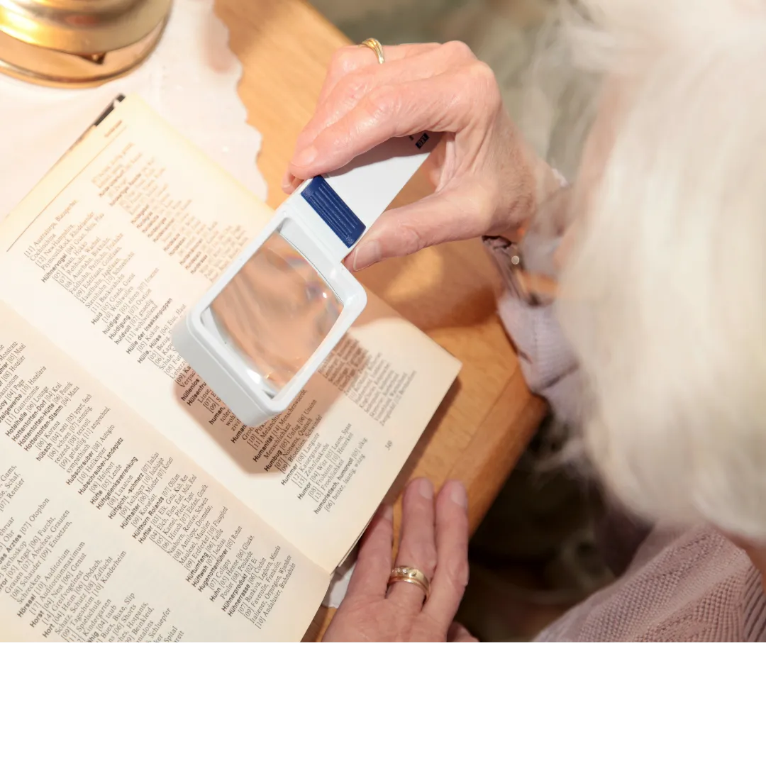 Lady with Macular Degeneration using magnifier to reaed