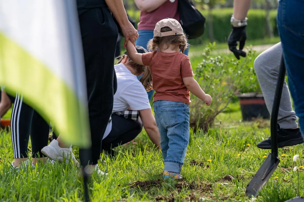 A picture of a child holding their parent’s hand in a crowded space, a fitting example of a situation in which someone would have to learn how to find a lost child if they go missing in a crowd.