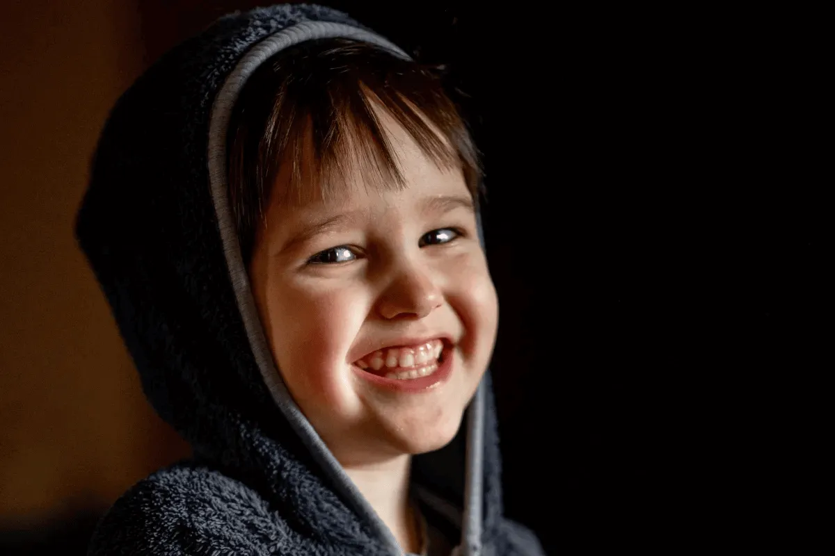 A happy and safe child, smiling because his parents make him feel secure after taking safety measures, teaching him what not to do and what to do, and using anti-kidnapping devices like My Family ID.