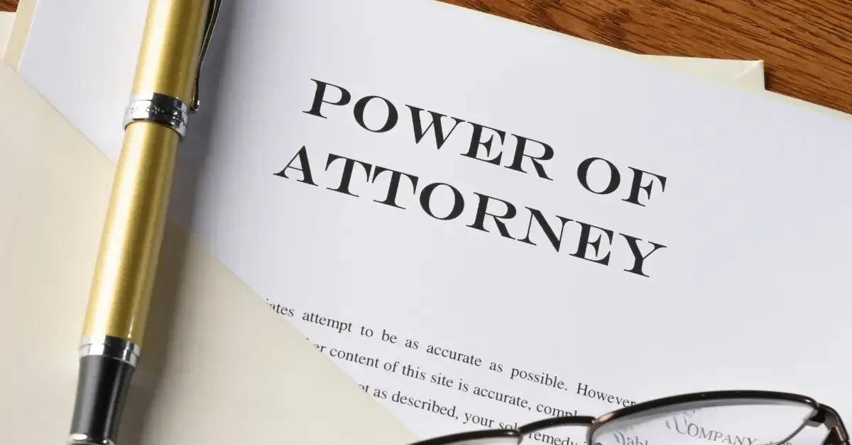 A document titled “Power of Attorney” with a gold pen and a pair of eyeglasses resting on top.
