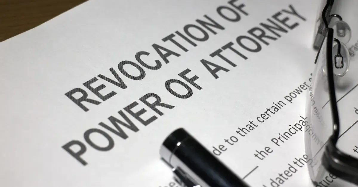 A document titled “Revocation of Power of Attorney” with a black pen and a pair of eyeglasses resting on it.