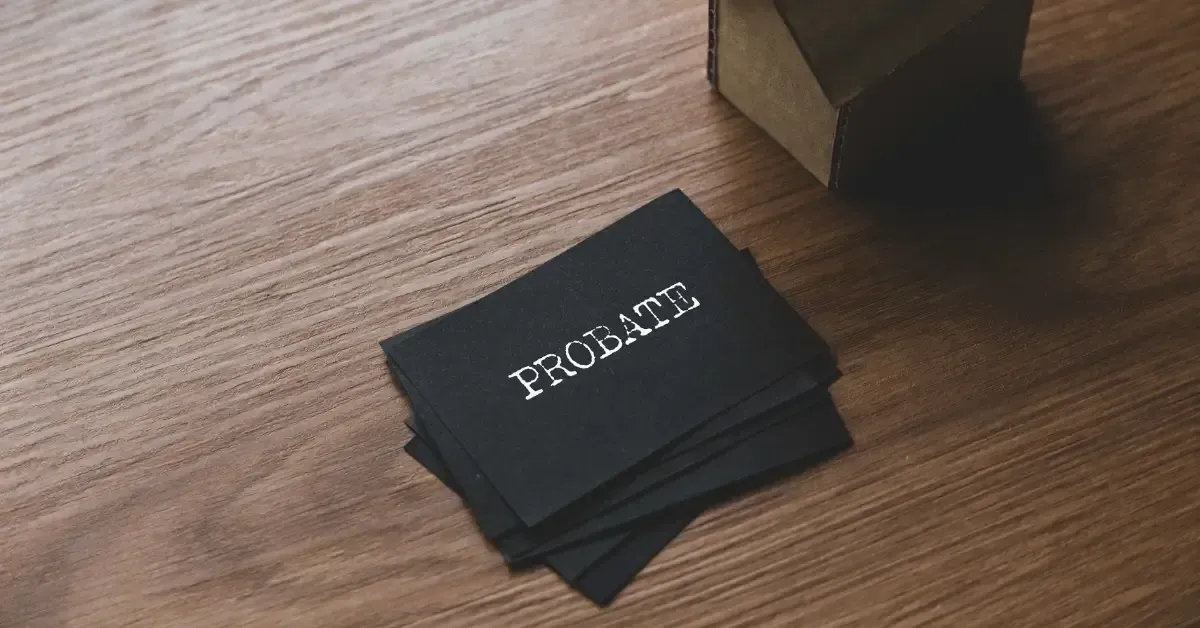 A stack of black cards with the word “PROBATE” printed in white, placed on a wooden surface next to a cardboard box.
