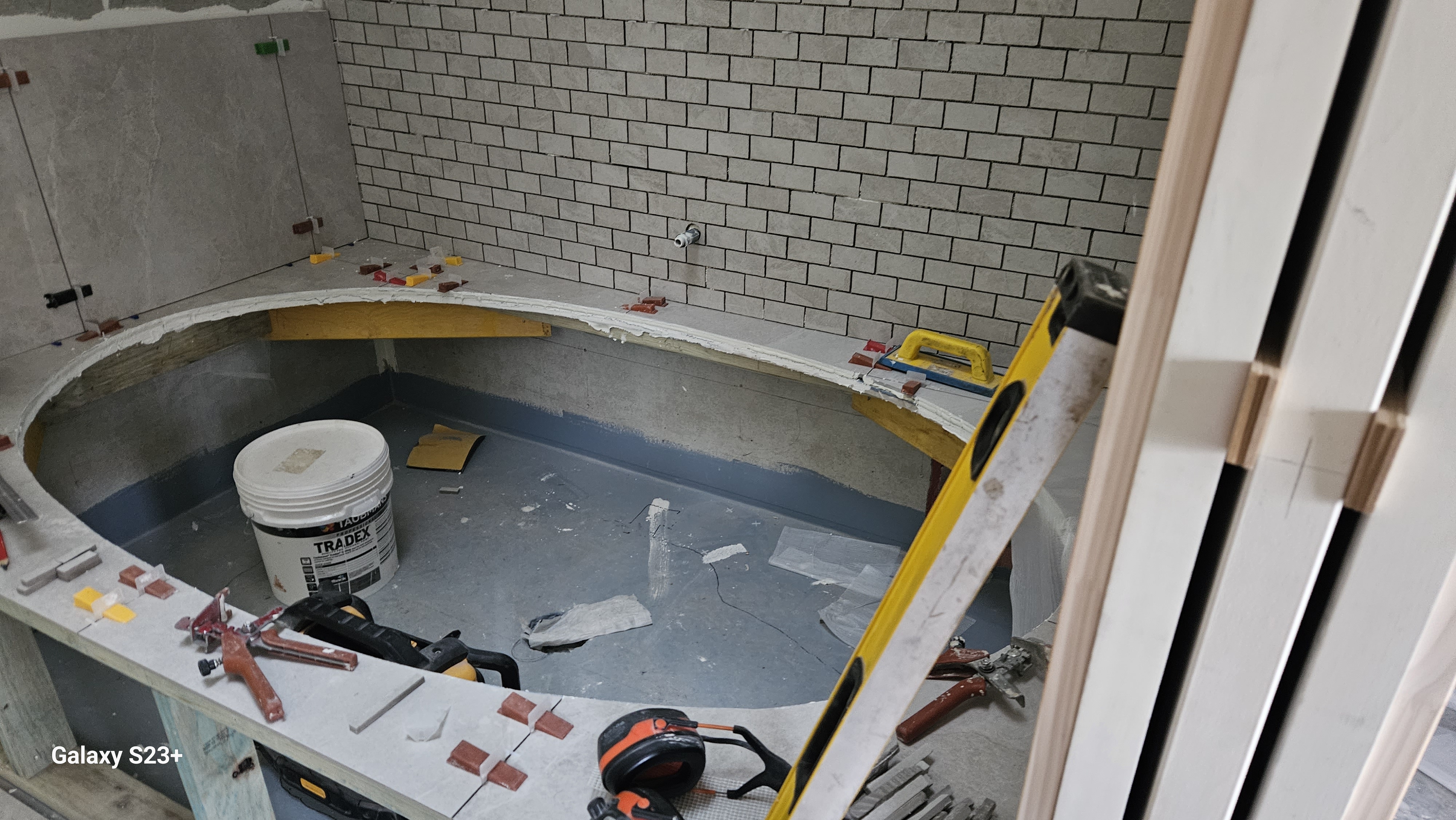Experienced tiler laying intricate porcelain tiles in a regional Australian bathroom, demonstrating precision set-out, waterproofing standards, and professional trade workmanship.