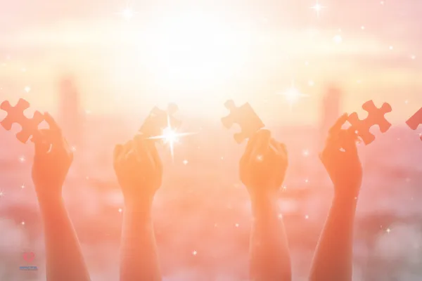 Hands holding glowing puzzle pieces toward the light, symbolizing clarity, connection, and the beginning of a healing journey.
