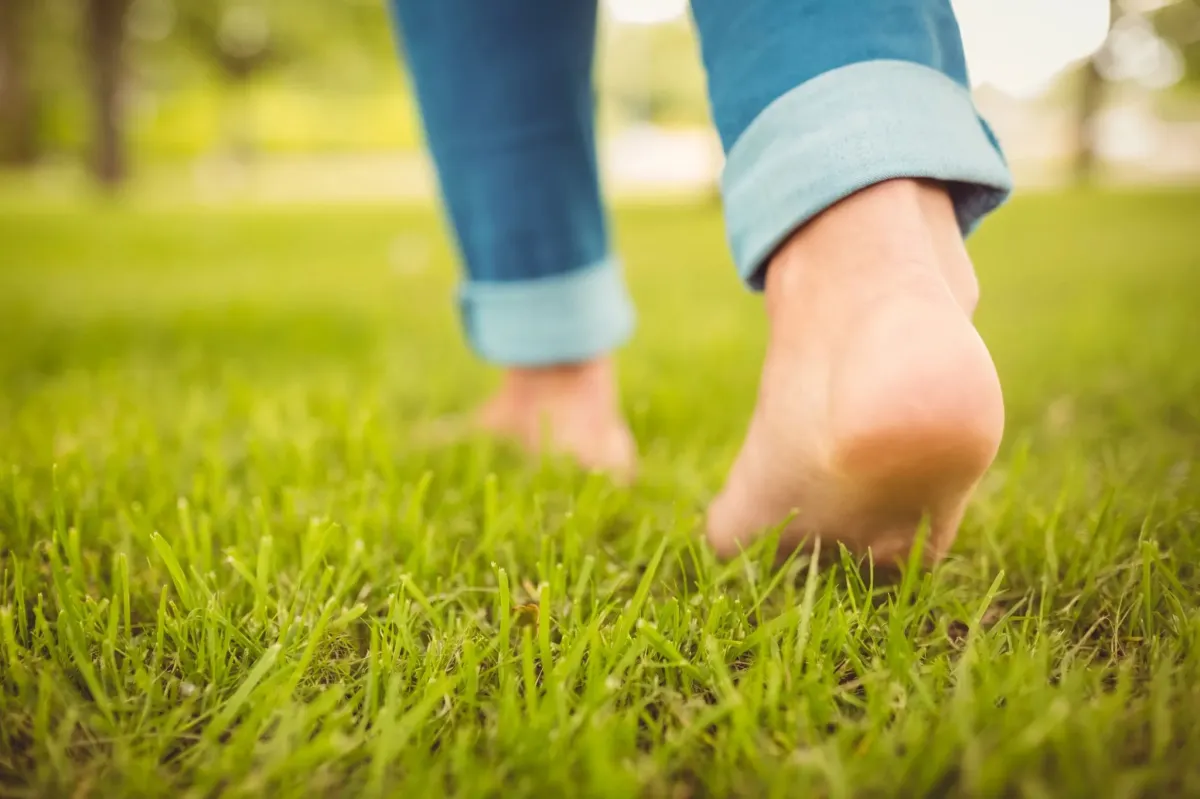 Client practicing grounding barefoot on grass during a Wellness Academy USA San Diego personal training session