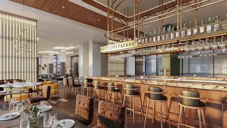 Sleek bar with marble counter, plush seating, and hanging glassware in upscale decor.