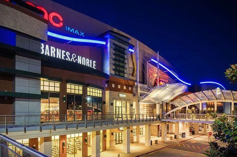 Brightly lit mall with Barnes & Noble, AMC IMAX, and Cheesecake Factory at night.