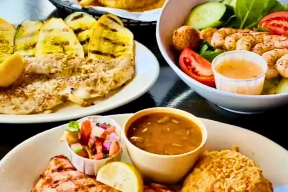 Grilled fish paired with rice, salad, soup, and fried side dishes.