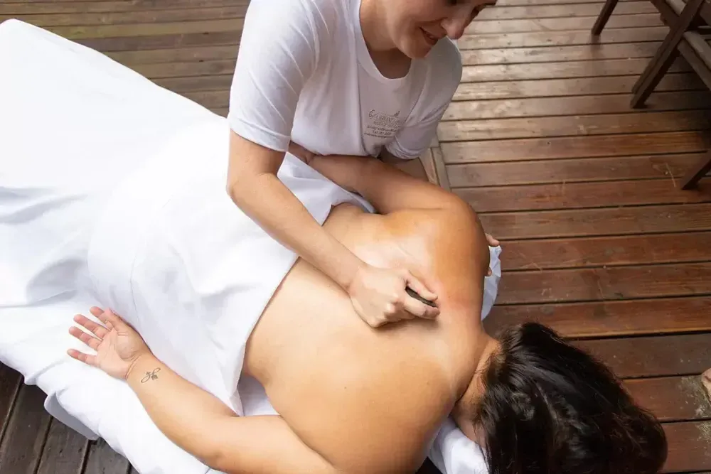 Relaxing back massage session on wooden deck in a serene outdoor setting.
