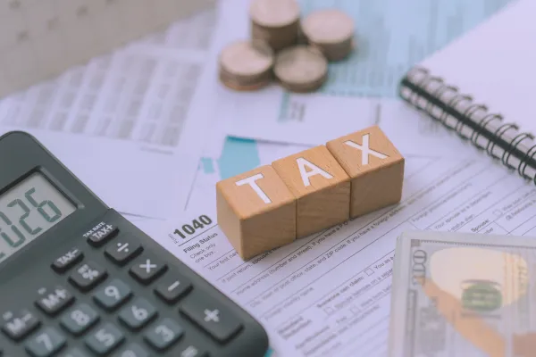 A partially visible IRS Form 1040 (U.S. Individual Income Tax Return) serves as the primary backdrop.