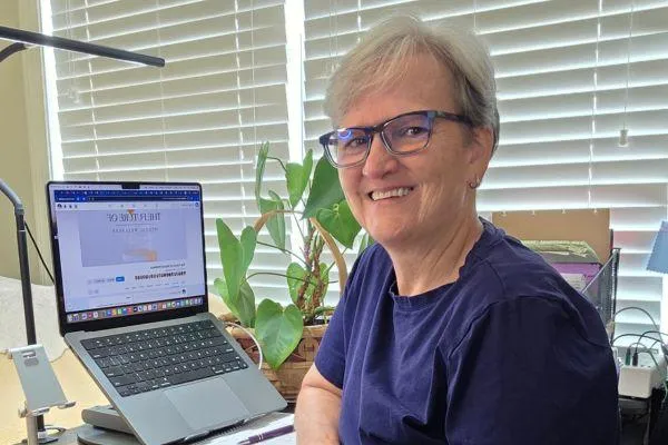 Woman working on a laptop with a notebook beside her—representing building a business with ease and intention