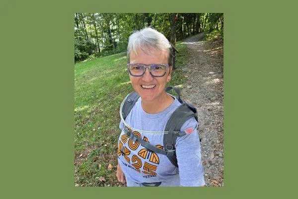 Claudette smiling on a wooded walking trail, symbolizing renewal and the path forward after healing.