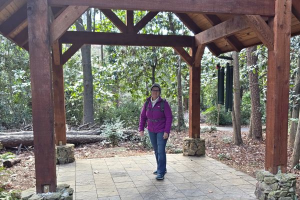 Claudette standing beneath a wooden pavilion on a forest trail, symbolizing a calm, reflective moment during her weight management and wellness journey