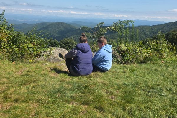 Woman and child sitting quietly on a mountain overlook, reflecting on healing, calm, and rebuilding strength naturally