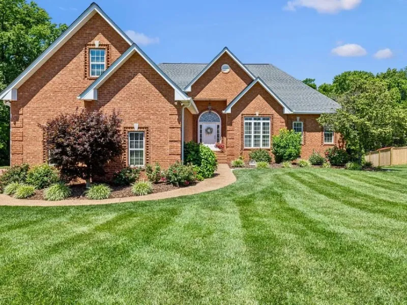 large brick home in tennessee with green healthy lawn