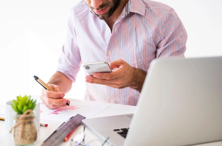 [Man reviewing business data on his phone, considering Pay Per Call campaigns to boost conversions