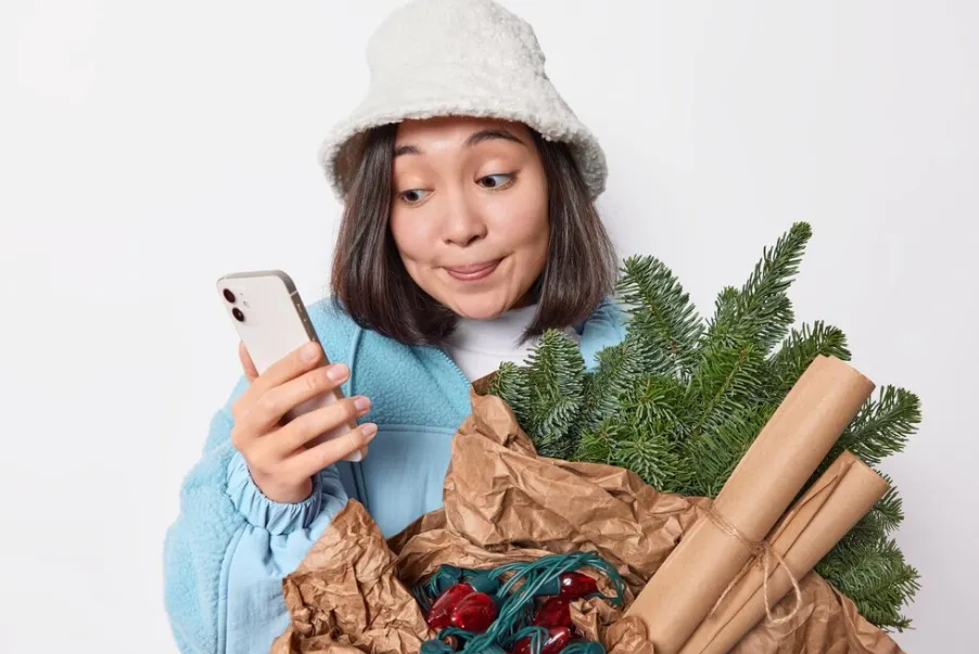 Woman checking her phone with holiday items - seasonal Pay-Per-Call campaigns concept