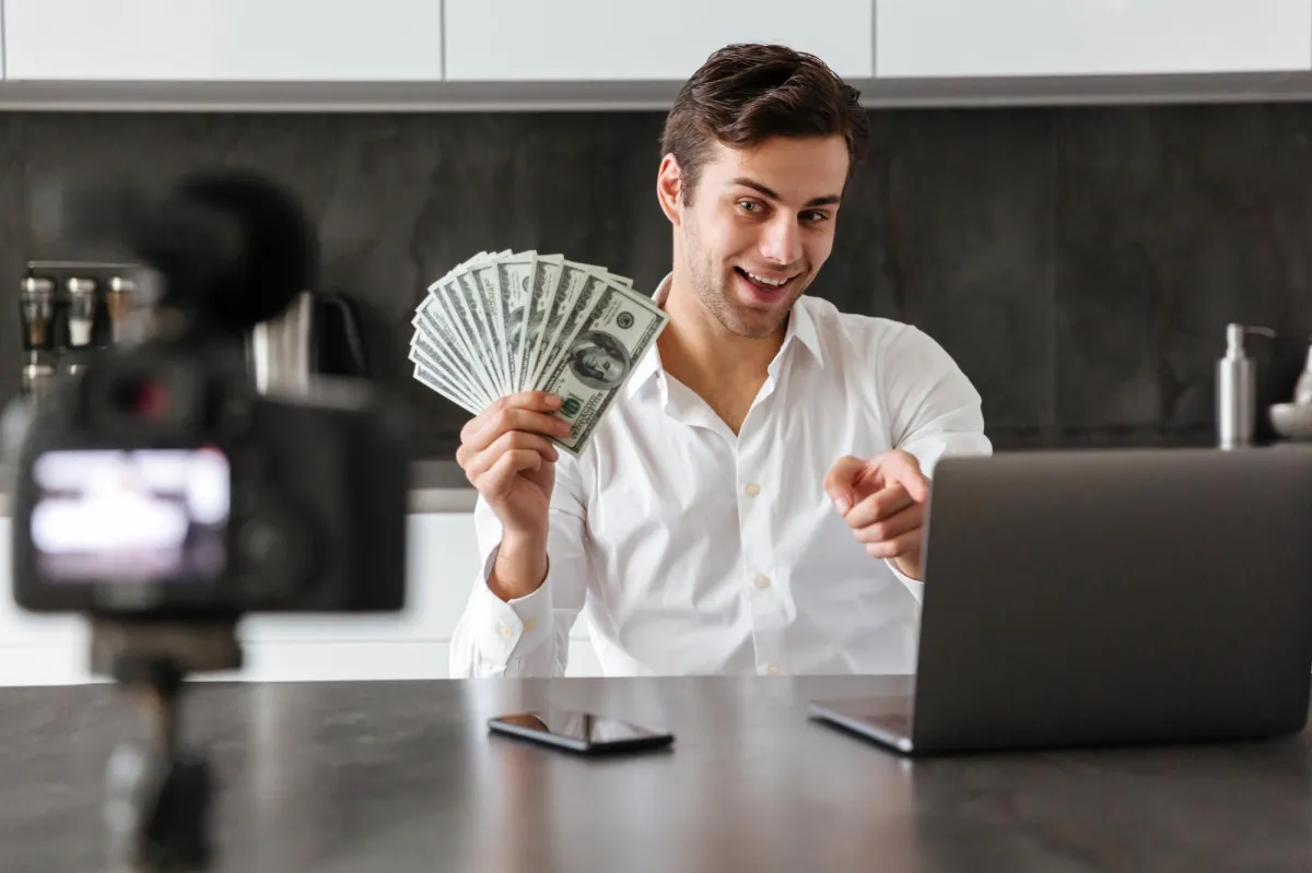 Man showing cash while recording video about pay per call business success online