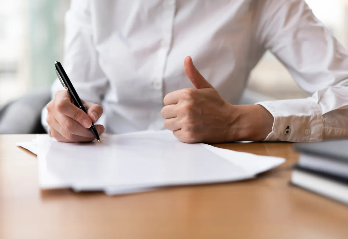 [Person signing documents with a thumbs-up gesture, representing Pay-Per-Call compliance and success