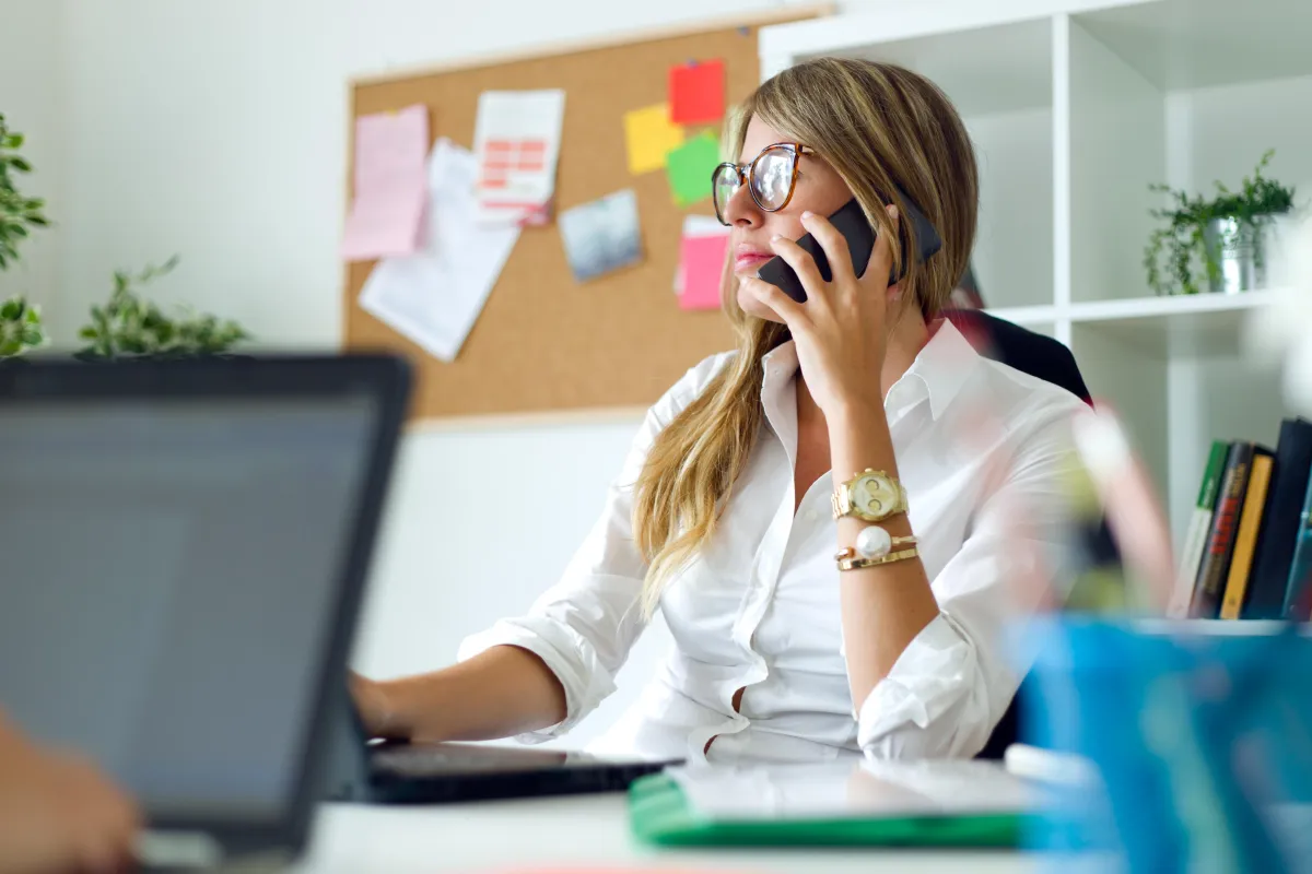 Businesswoman on a call at her desk, representing a Pay Per Call marketing campaign strategy