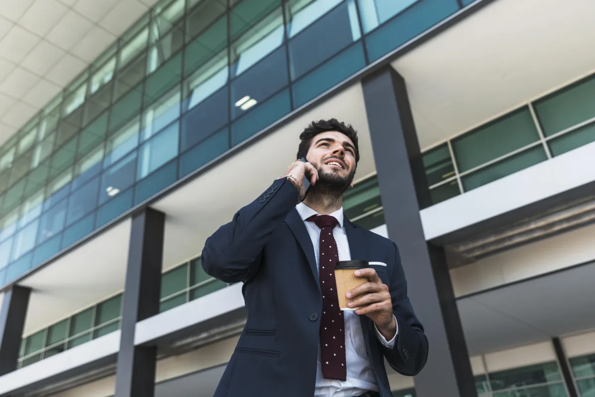 Businessman making a B2B phone call outside a modern office building