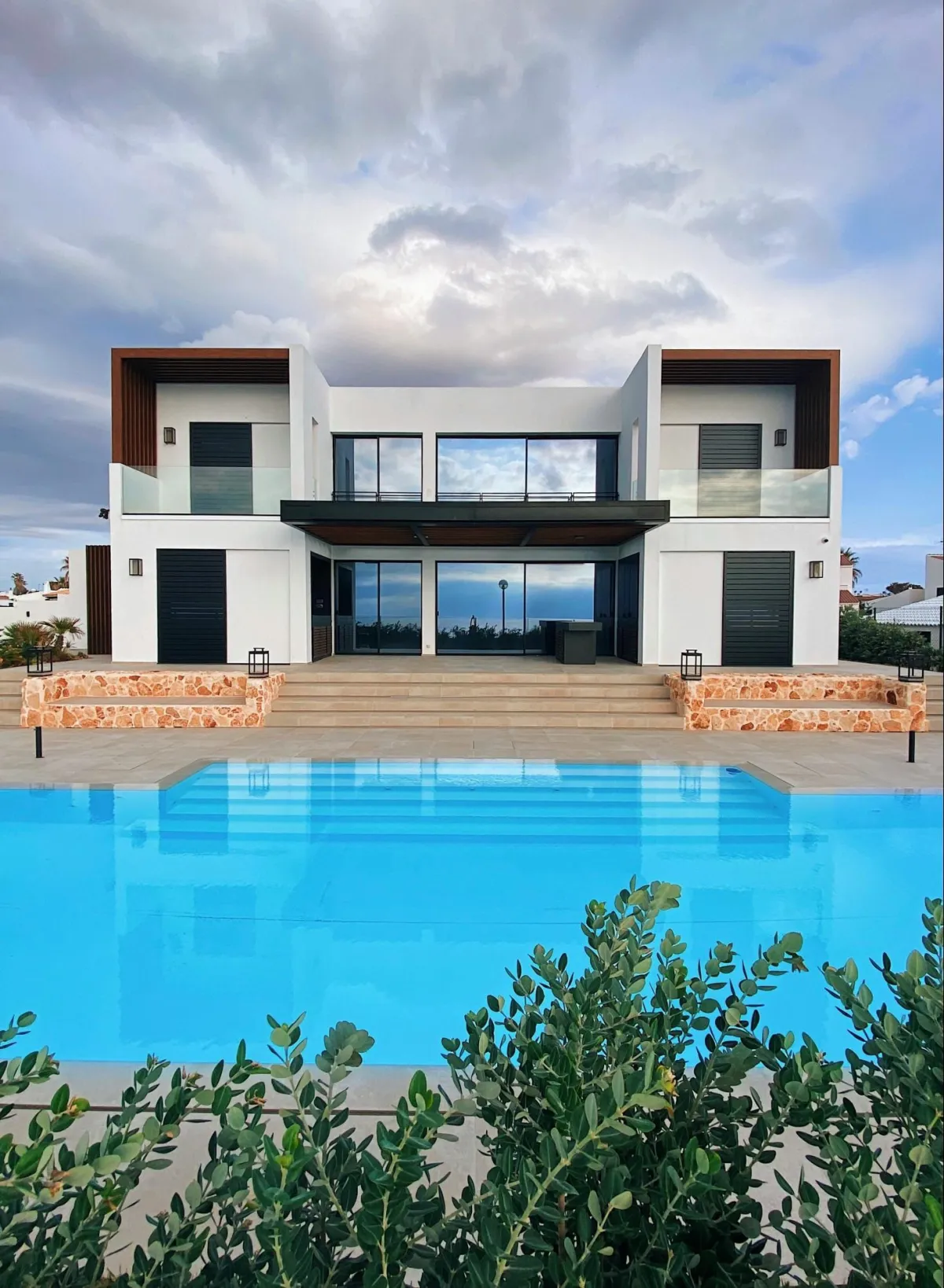 Modern luxury home with a sleek design, large glass windows, and a pool in the foreground.