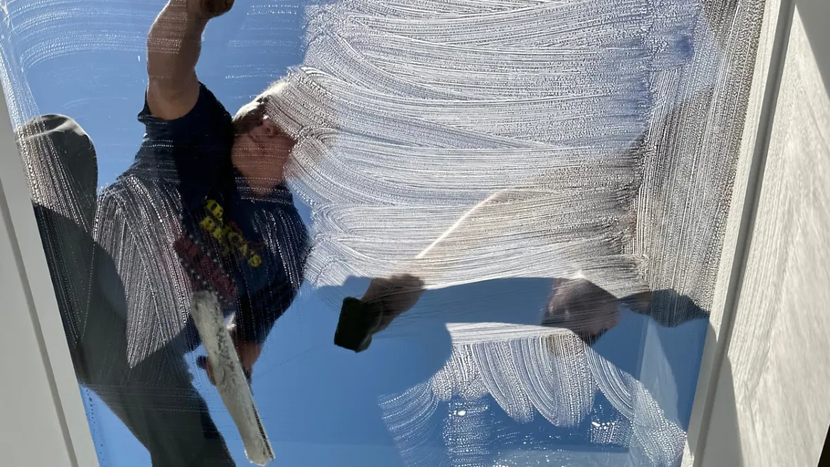 Window cleaner scrubbing a skylight from the outside on a sunny day in Santa Clarita, CA.
