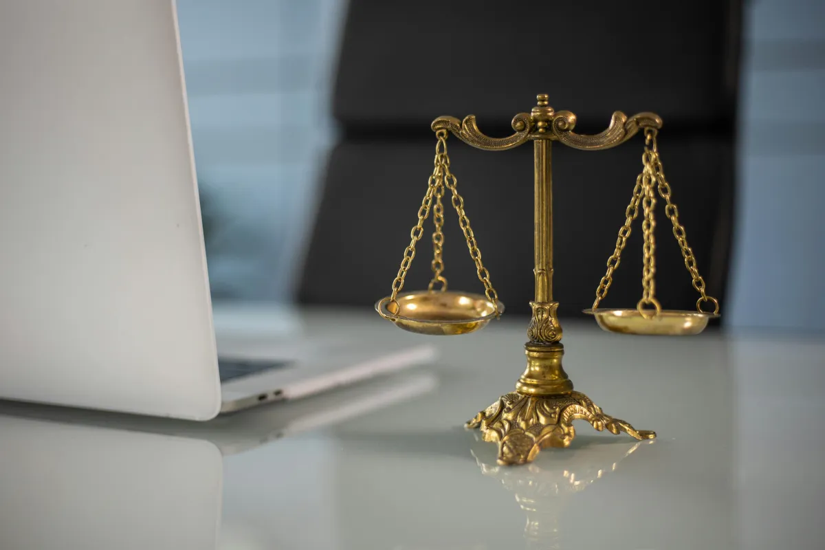 The scales of justice appear next to a laptop potentially opened to finalize an M&A purchase agreement