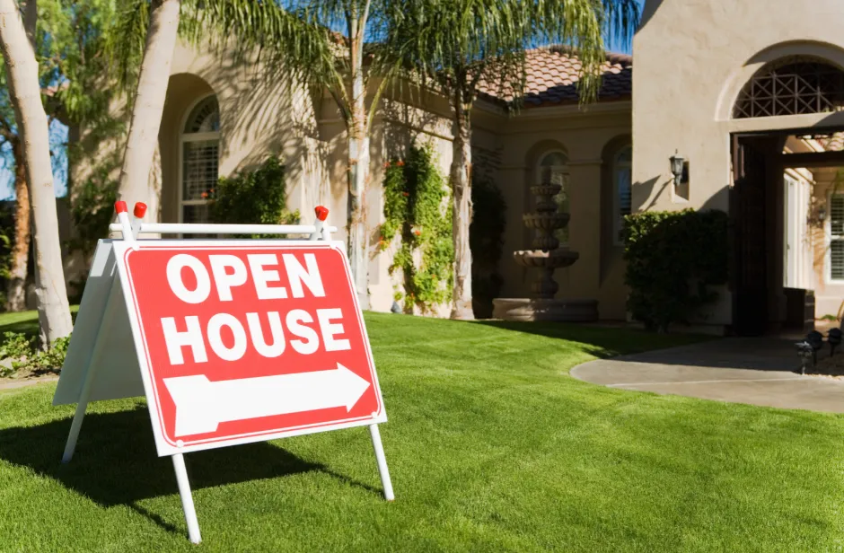 An Open House sign in front of a home in a tropical setting.