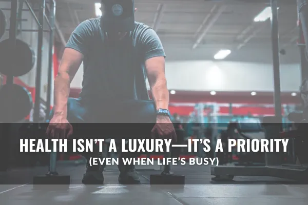 Person squatting down in a gym with dumbbells placed on both sides, head down