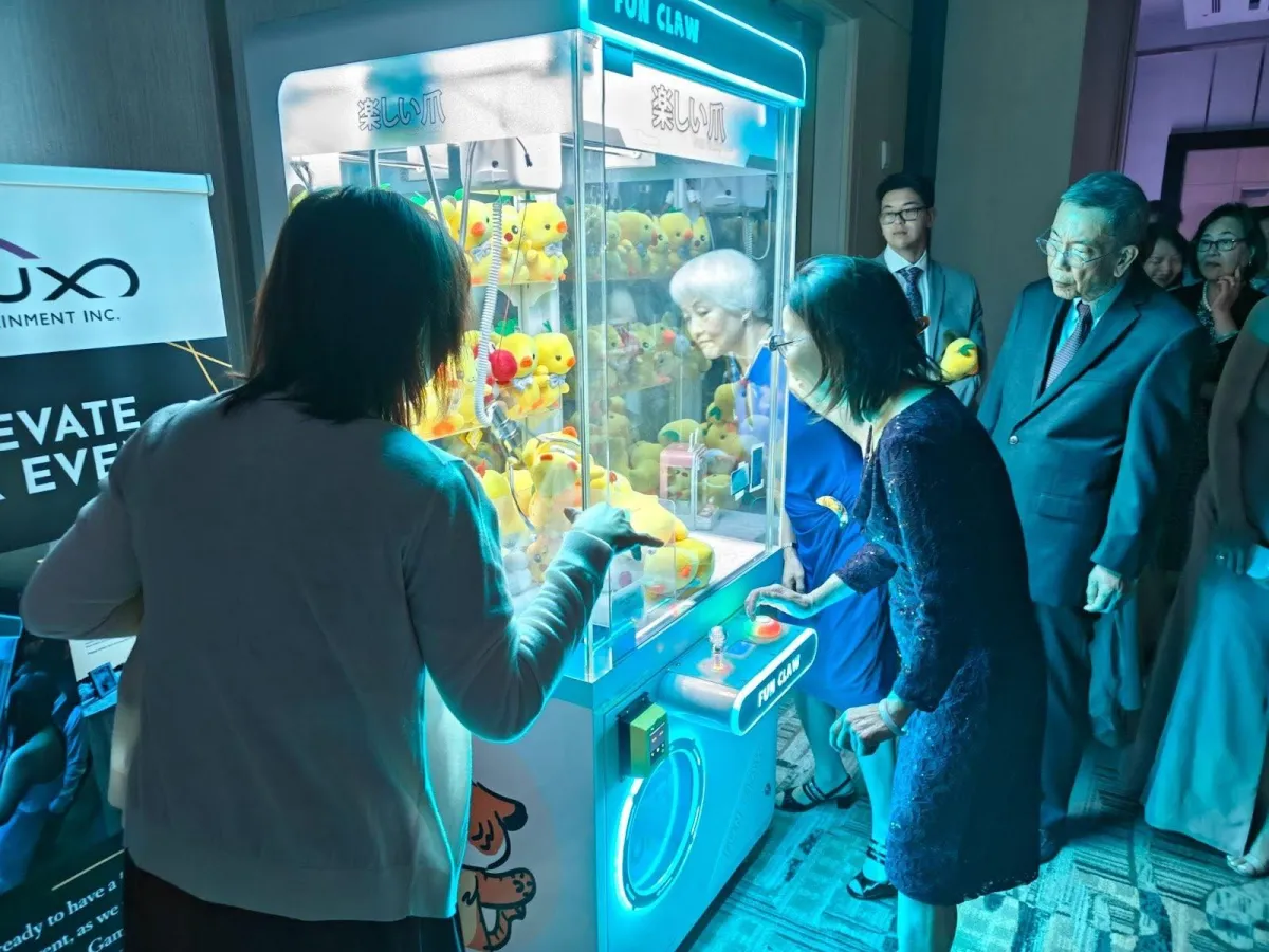 A group of wedding attendees playing on a Flux Entertainment Claw Machine they Rented for their wedding.