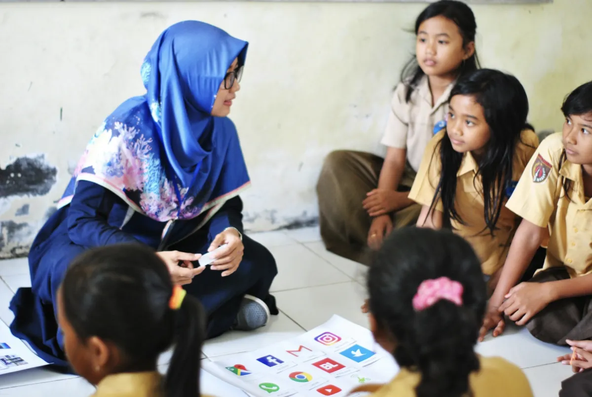 Teacher engaging with students in a classroom, promoting positive social interactions and communication skills through interactive activities