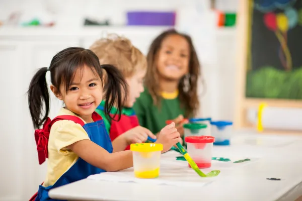 Preschool teacher guiding young children through an arts-based activity