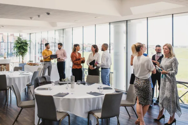 The image features a diverse group of smiling professionals engaged in a lively discussion, set against a modern office backdrop with bright, inviting colors. The atmosphere exudes positivity and connection, illustrating the theme of attracting like-minded individuals through positive energy and shared values in the business world.