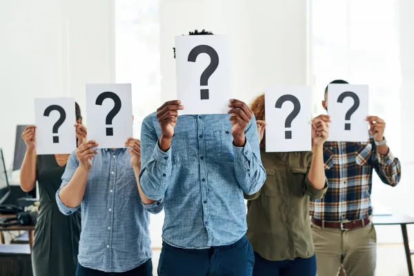 Businessmen holding a question mark card on their heads as a representation of the questions about the The How, What and Why of a Great Testimonial