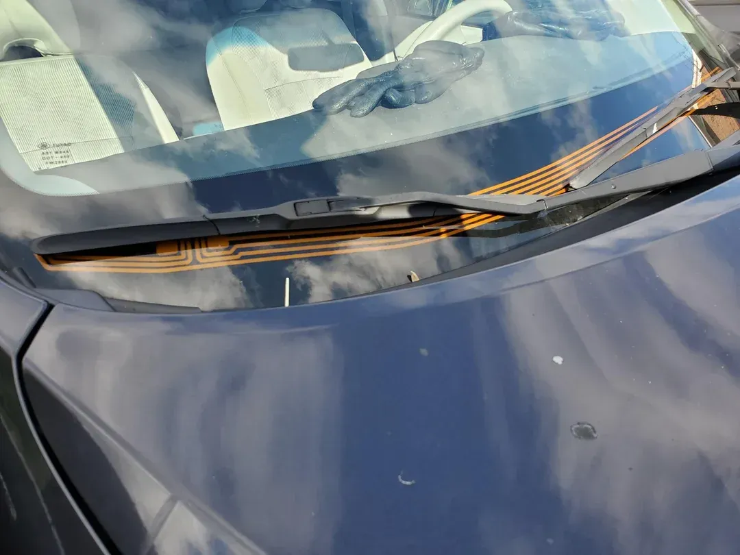 Heated wiper park system melting ice on a vehicle windshield