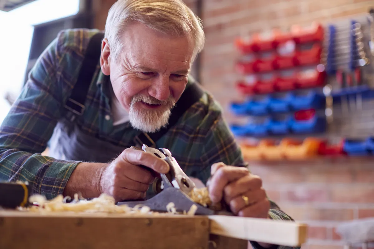 older man working on carpentry to make toys