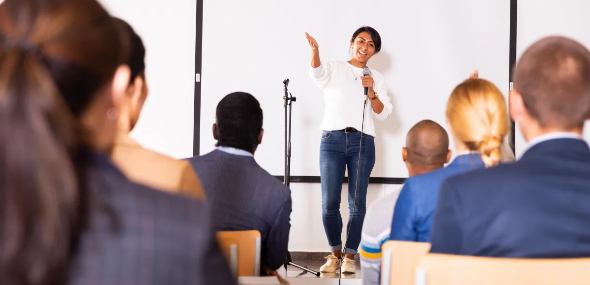 woman standing in front of a screen speaking to a group
