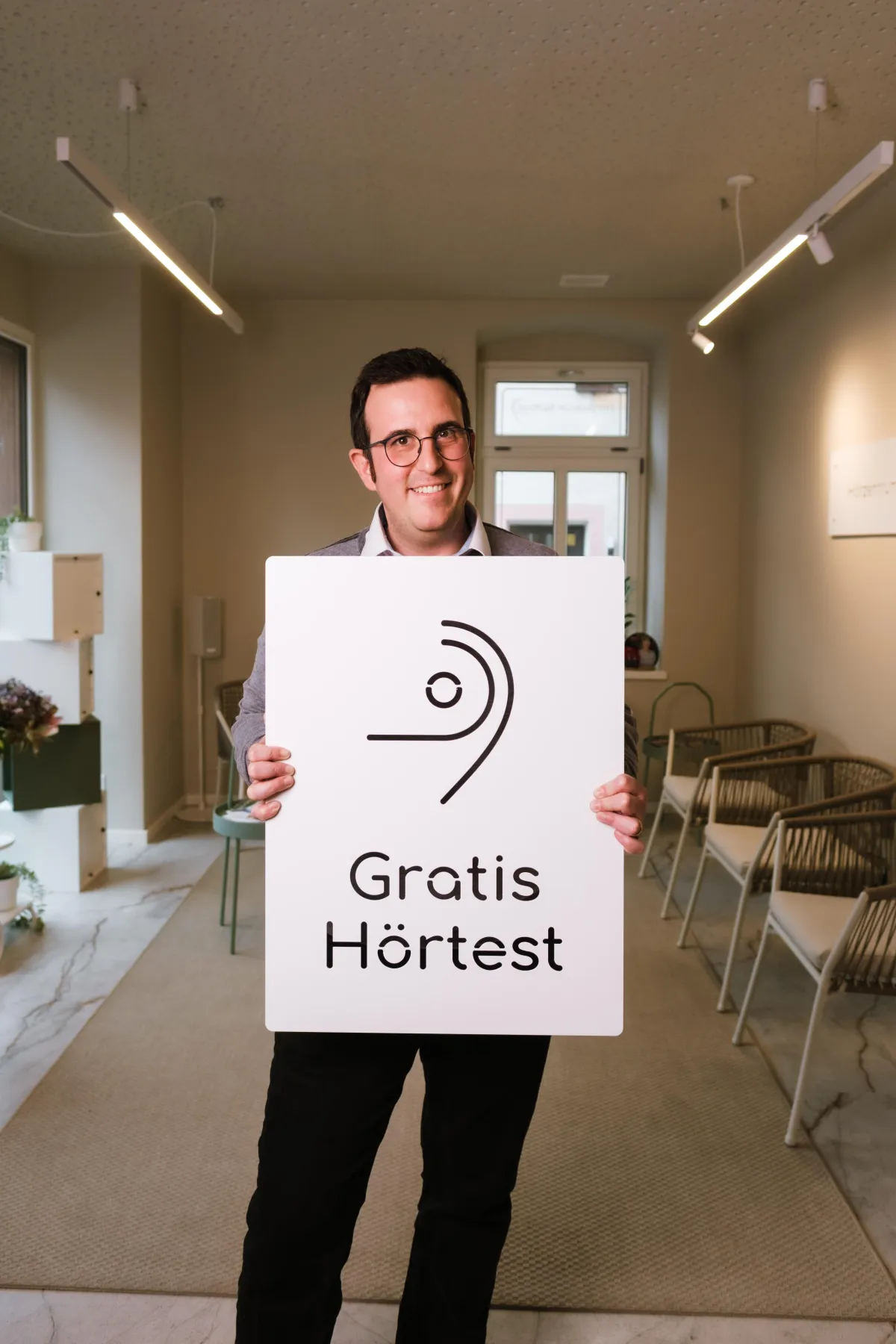 Person hält Schild mit Aufschrift: Gratis Hörtest.