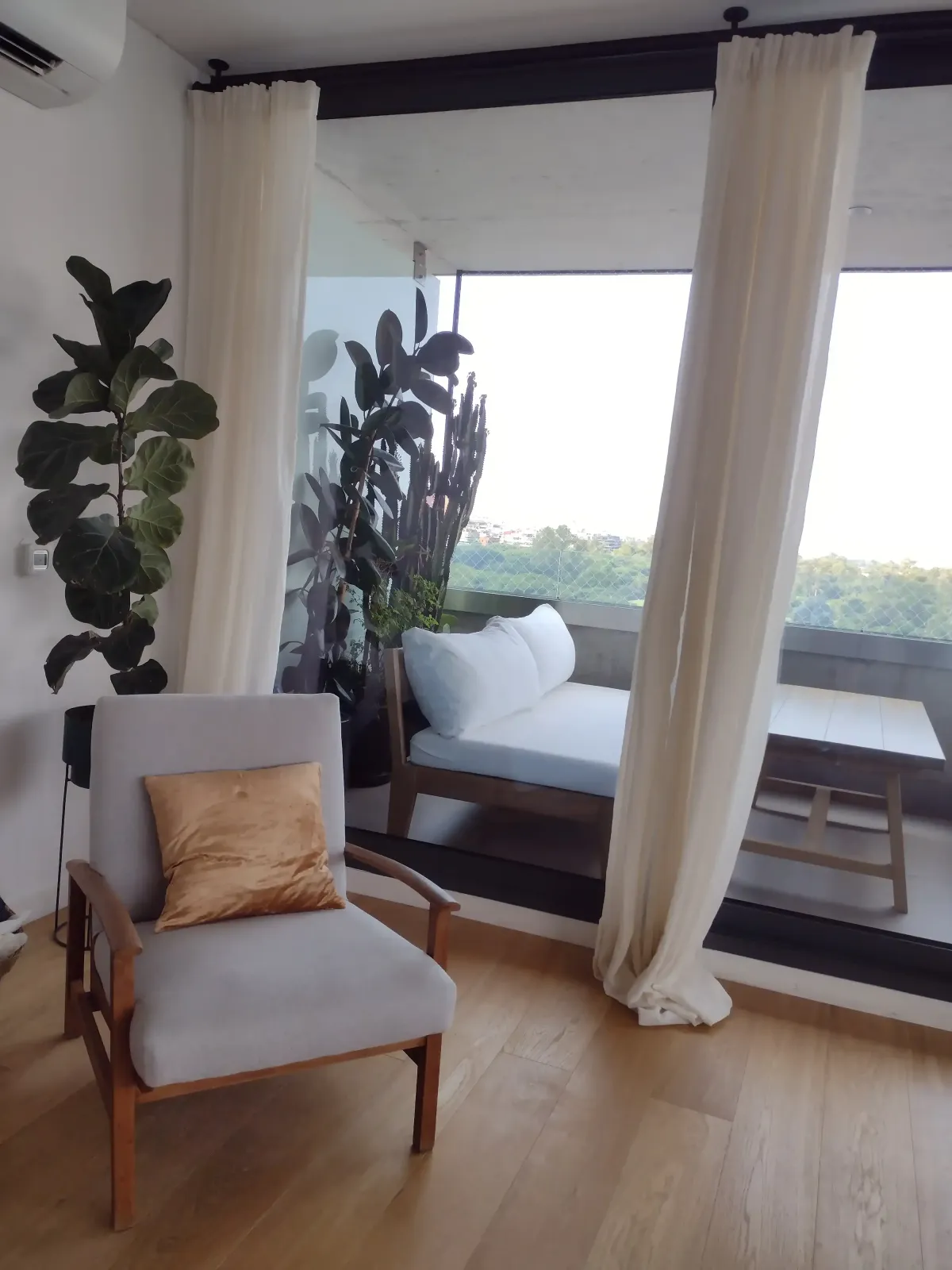 Habitación cómoda con cortinas blancas de tela translúcida, ventanas con control solar